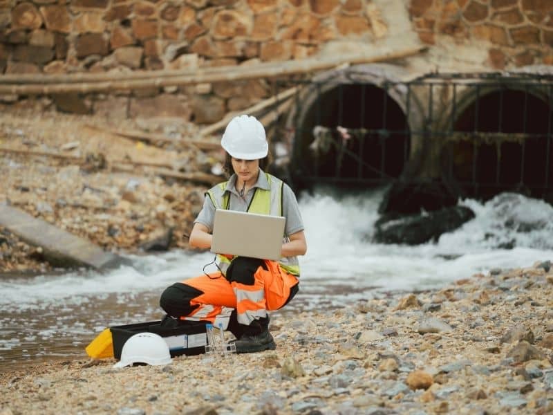 Engineer evaluating stormwater drainage infrastructure near culvert outlets to support accurate construction and long-term system performance.