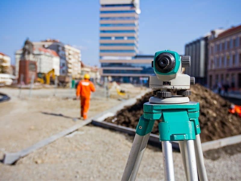 Surveying instrument set up on an urban development site to support boundary survey findings before construction planning.