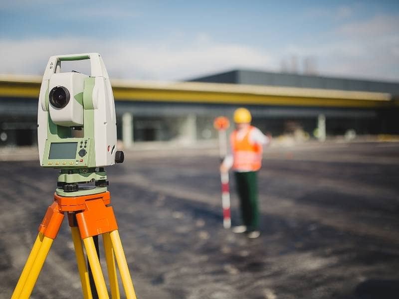 Survey equipment and surveyor collecting field measurements for an ALTA survey at a commercial property in Wilmington.